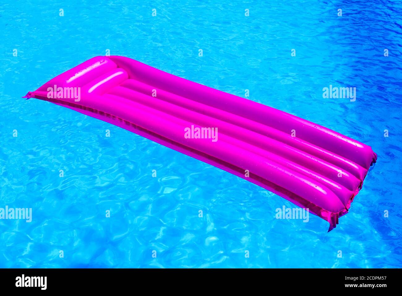Pink air mattress floating on water of swimming pool Stock Photo
