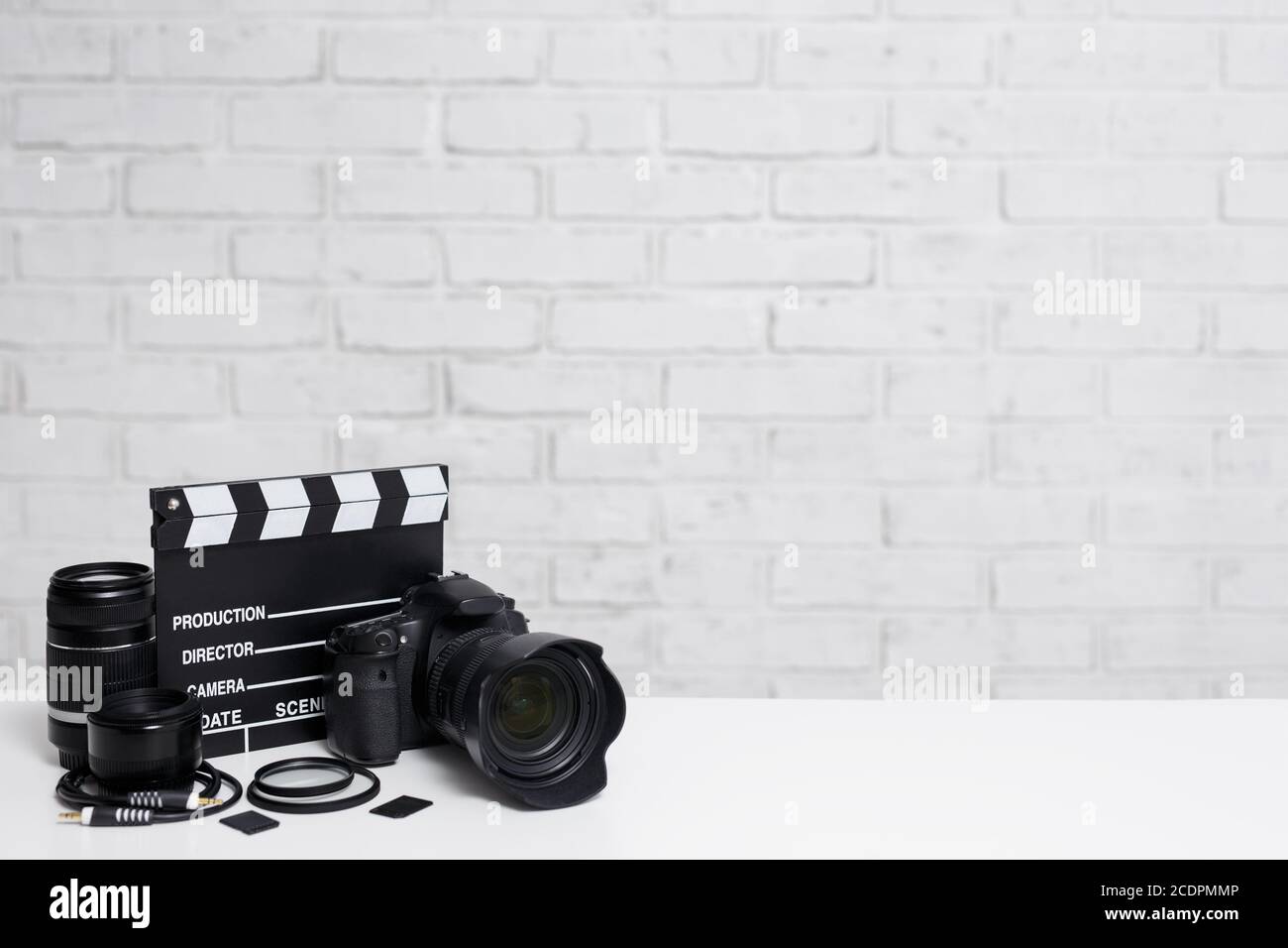 videography and photography equipment - modern dslr camera, lenses,  filters, memory cards and clapper board over white brick wall background  with copy Stock Photo - Alamy