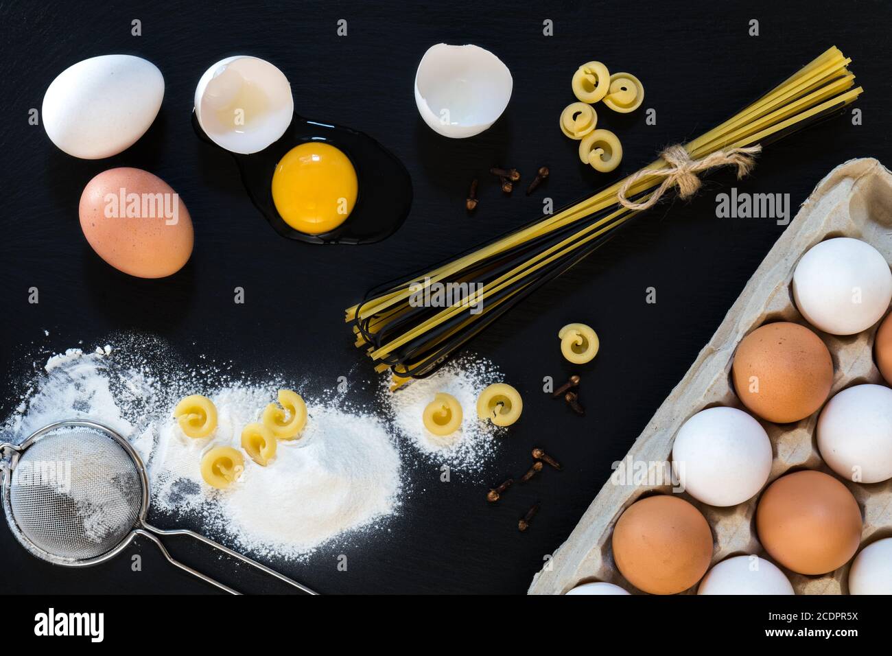 Traditional and black uncooked Italian pasta Linguine with white and brown chicken eggs Stock Photo