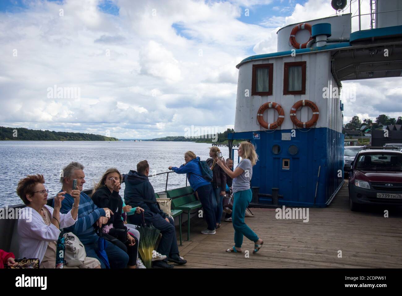 Tutaev, Russia - July 16, 2029 Volga landscape with a high opposite shore with a white church. People on the ferry at the side of the ferry across the Stock Photo