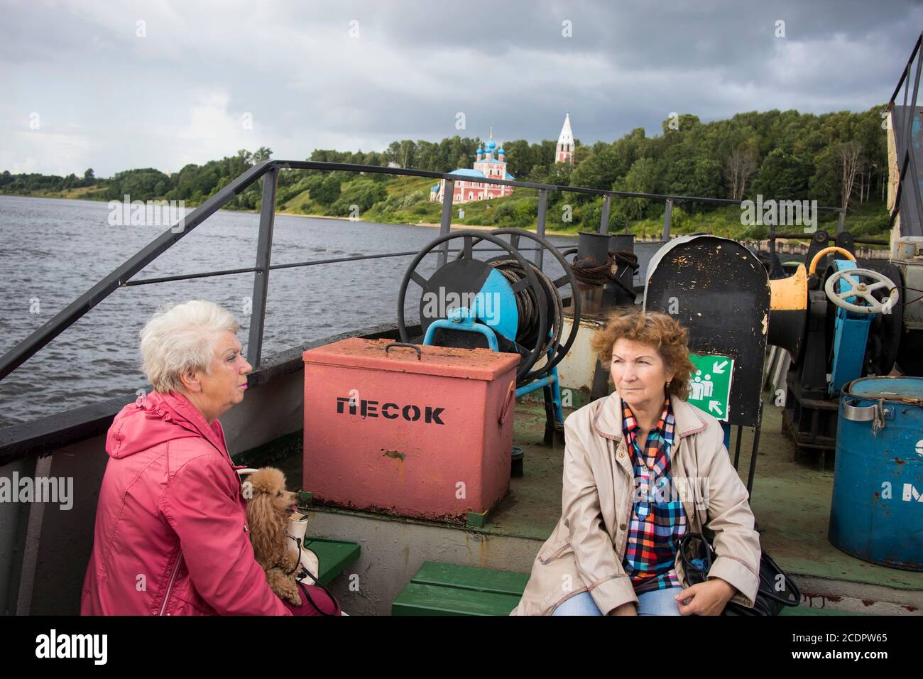 Tutaev, Russia - July 16, 2029 Volga landscape with a high opposite shore with a white church. People on the ferry at the side of the ferry across the Stock Photo
