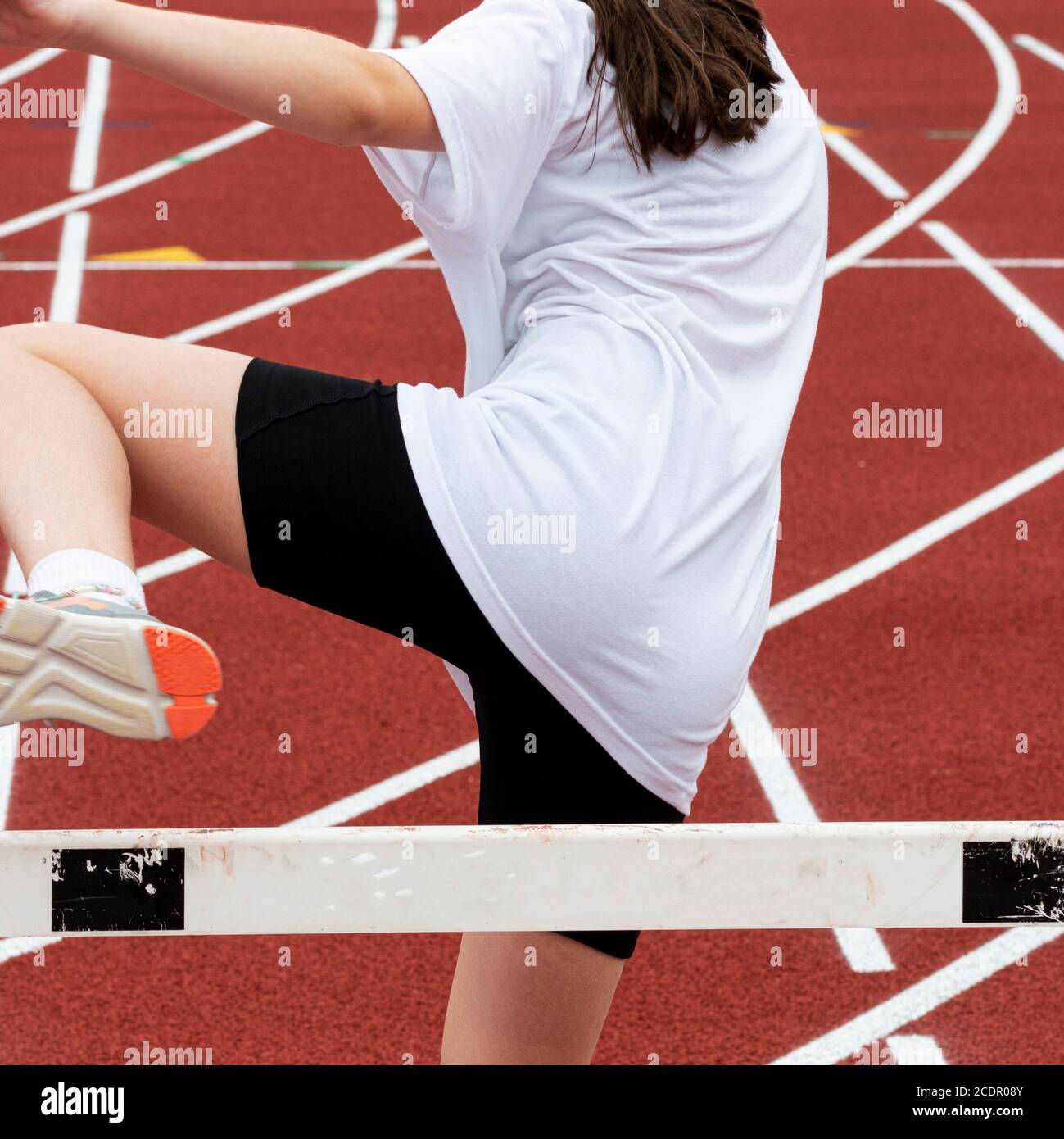 A young girl is at running summer camp learning how to run over the