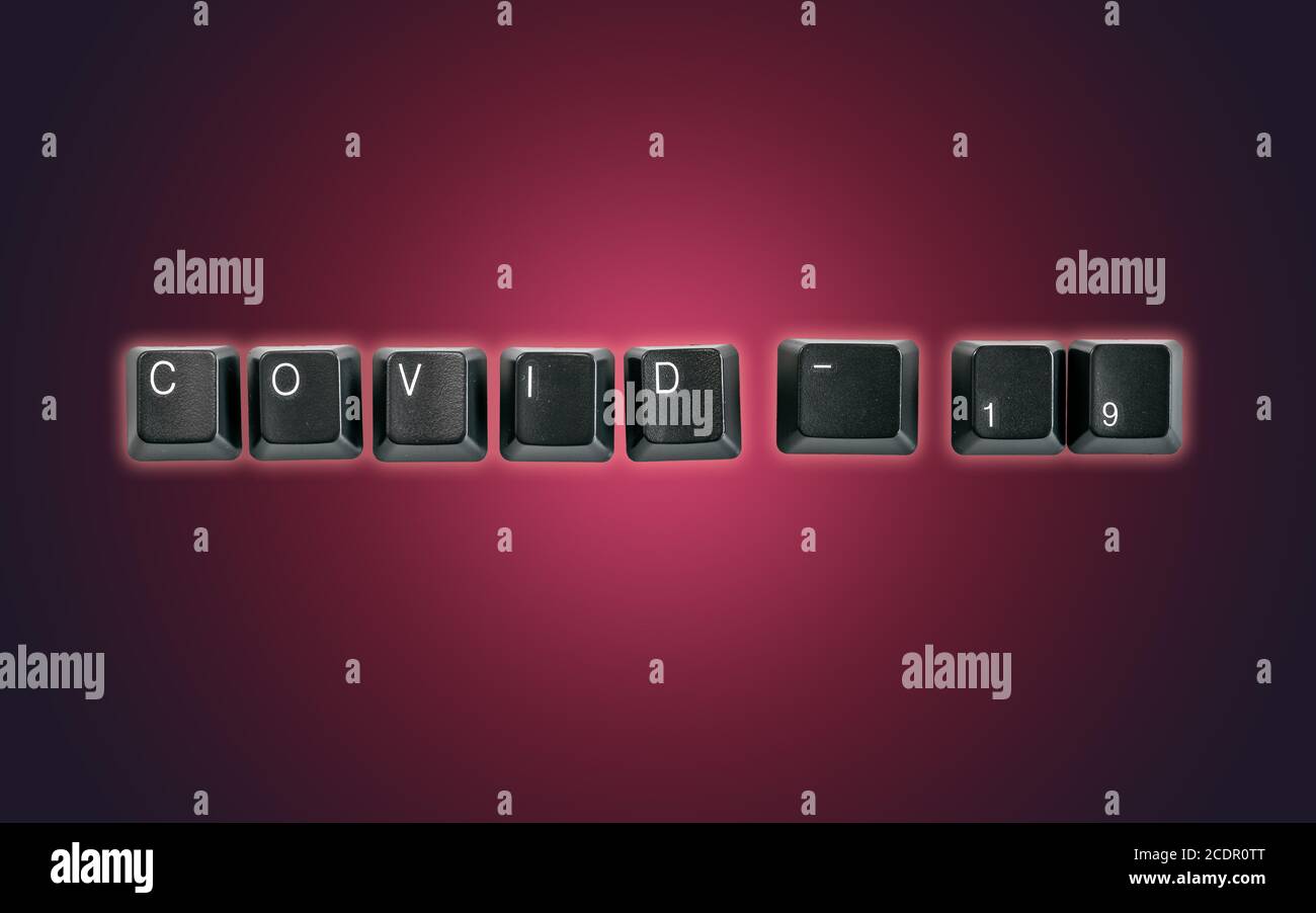 Computer keyboard keys spelling Covid-19, isolated on a dark background Stock Photo