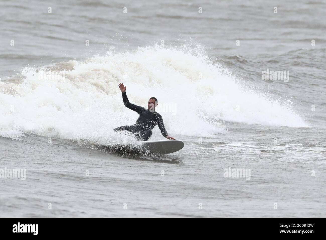 A surfer enjoys the rough seas in Scarborough, North Yorkshire. Picture date: Saturday August 29, 2020. Forecasters predict this Bank Holiday Monday could be the coldest on record for some parts of the UK as temperatures are expected to be well below average for the time of year. See PA story WEATHER Thunderstorms. Photo credit should read: Danny Lawson/PA Wire Stock Photo
