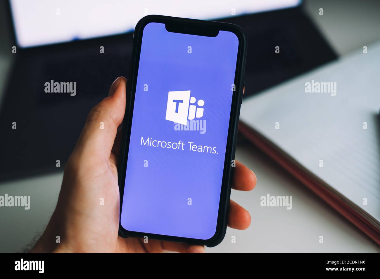 Hand holding iPhone with Microsoft Teams video call app logo on the