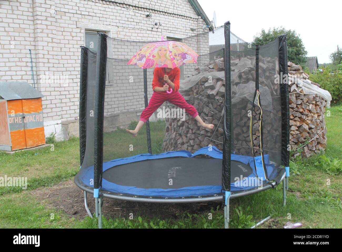 girl under bright umbrella play under rain  in the garden in last summer day on vacation Stock Photo