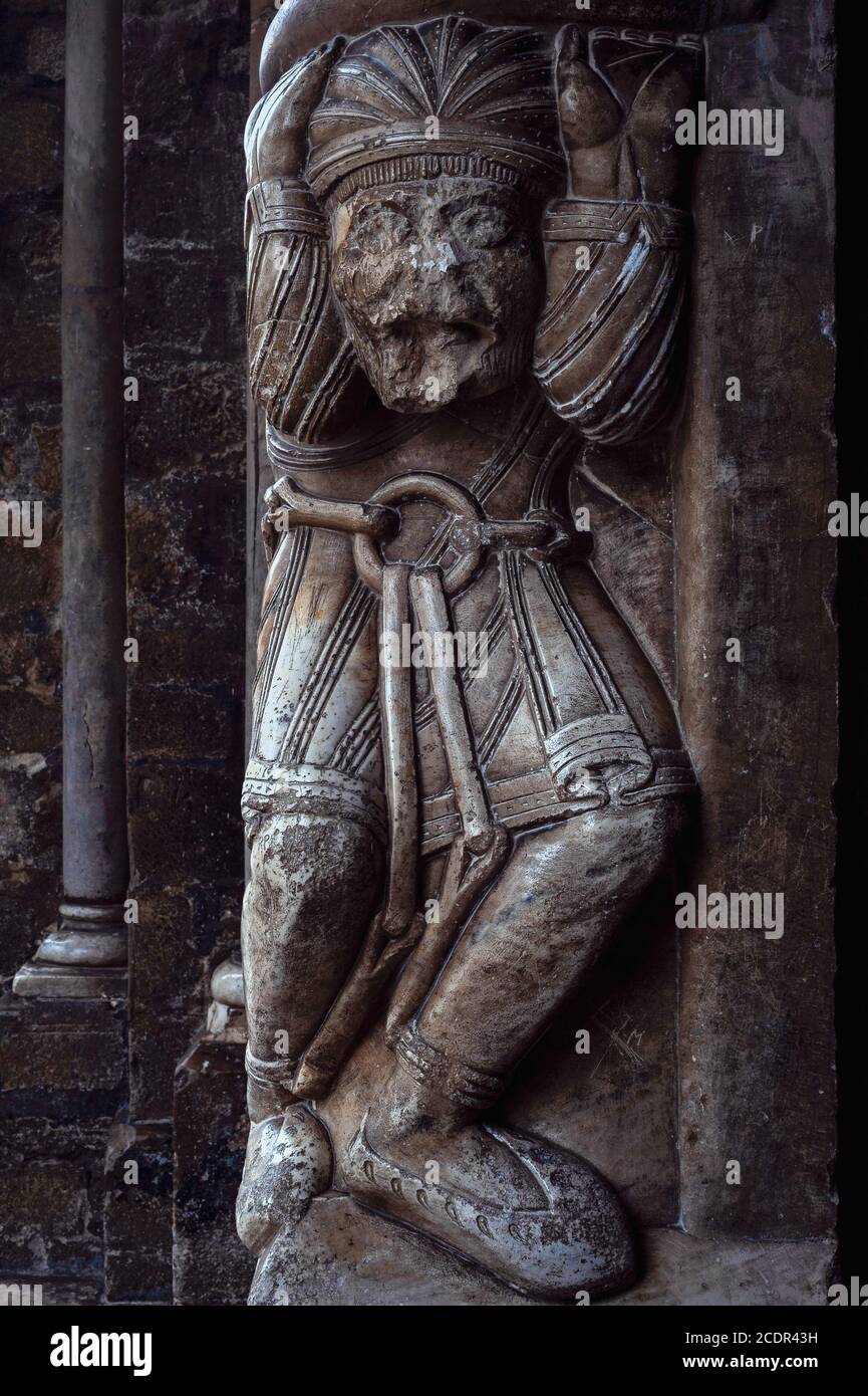 A shackled prisoner, knees buckling under the weight of his heavy