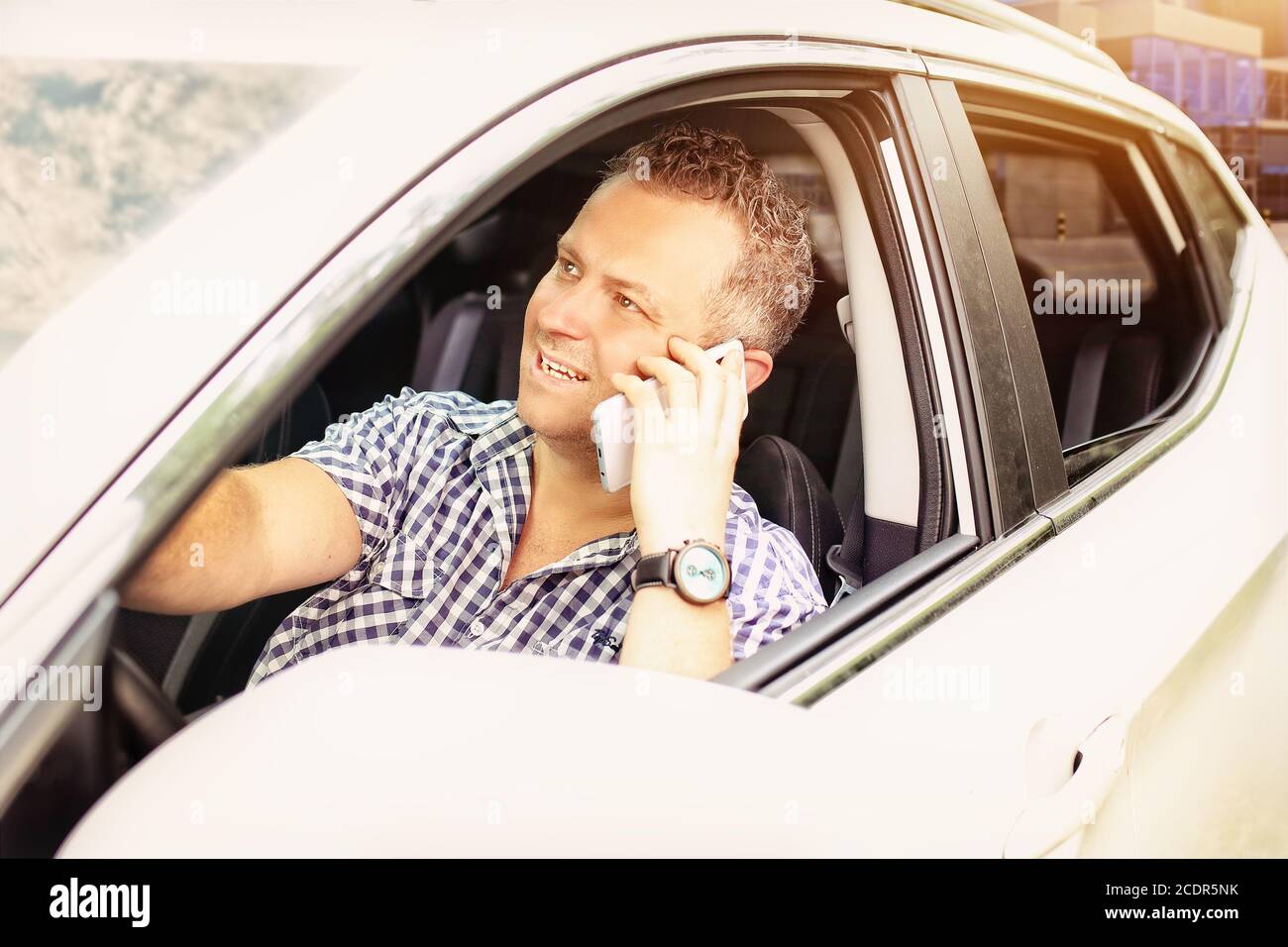 man uses a mobile phone while driving a car Stock Photo