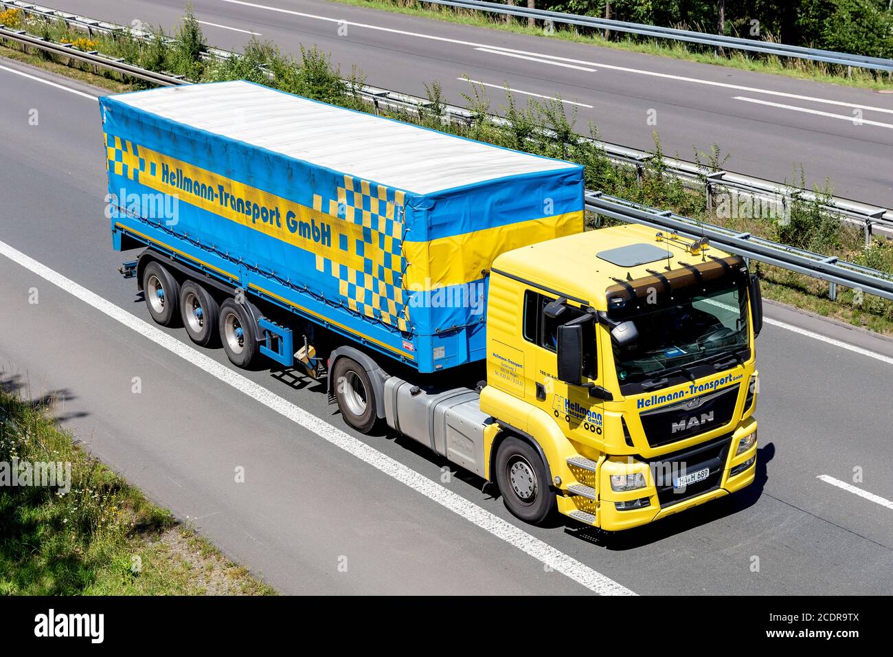 Hellmann MAN TGS truck with tarpaulin trailer on motorway. Stock Photo