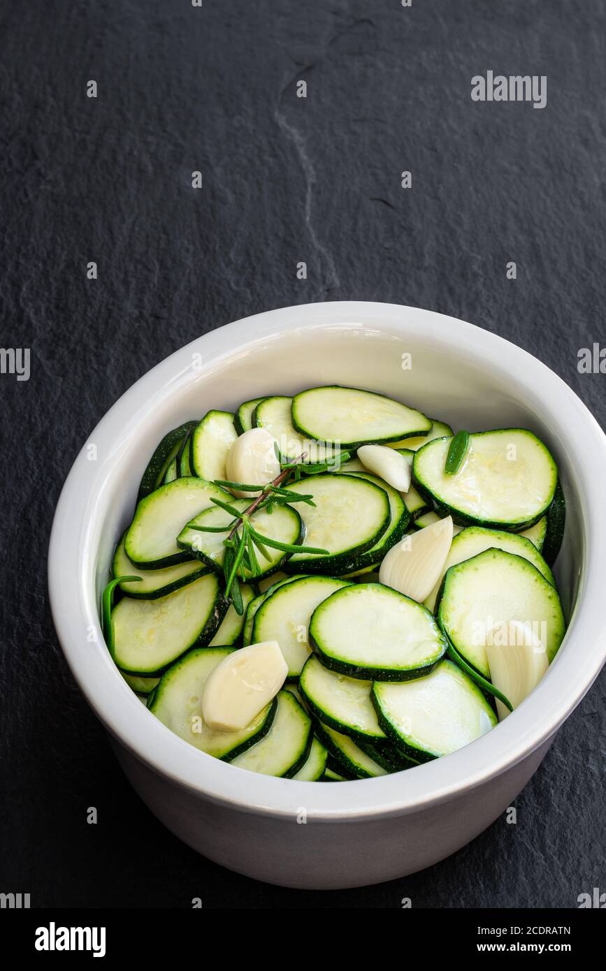 Marinated  zucchini slices in clay bowl on black stone background Stock Photo