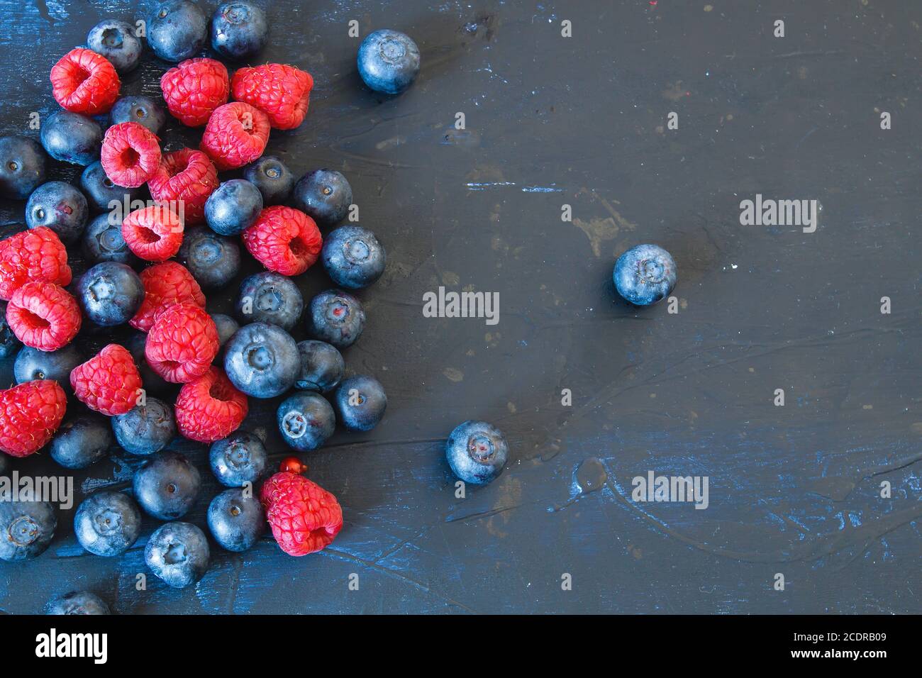 Raspberries and blueberries on dark blue background Stock Photo