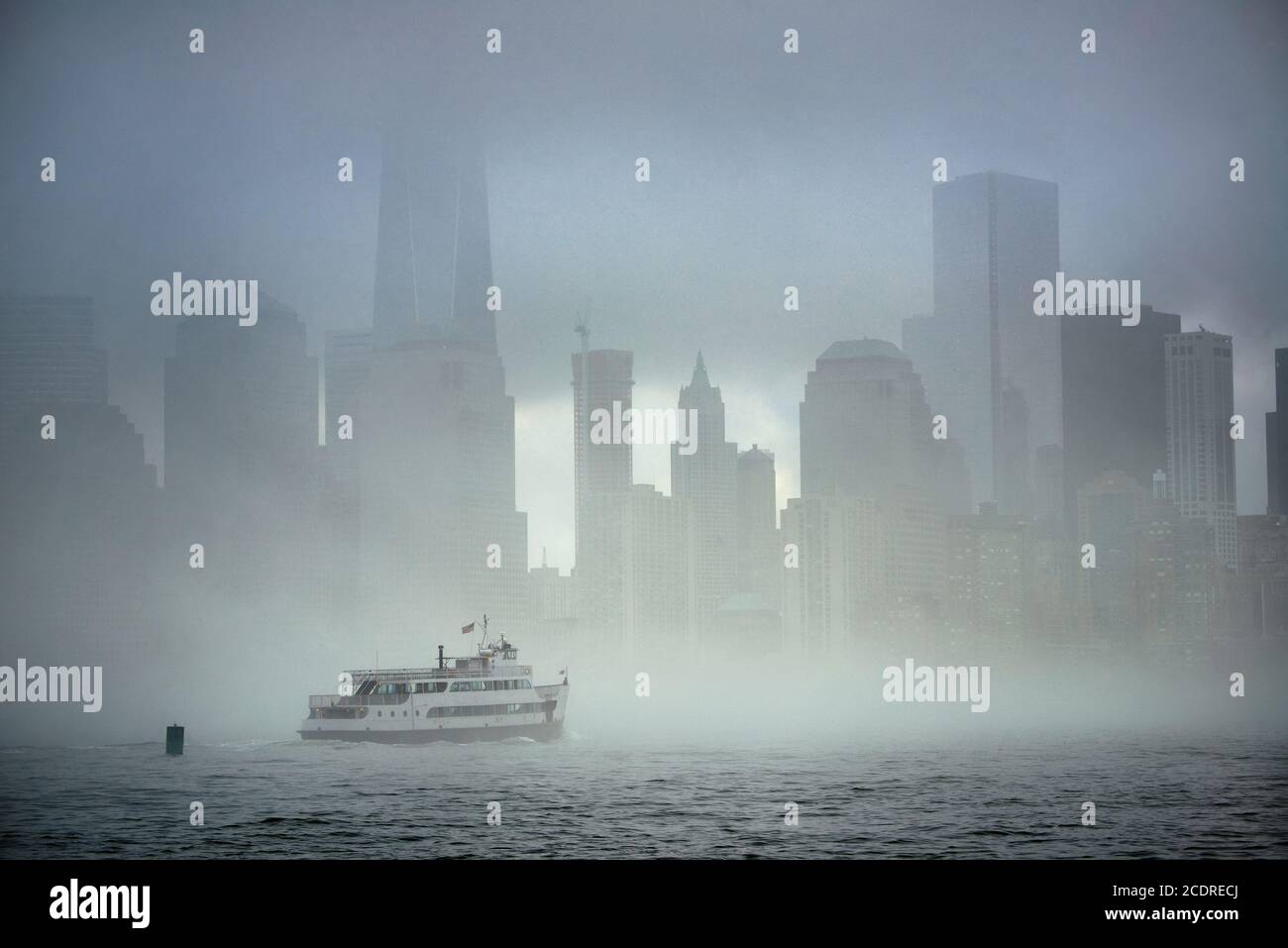 Downtown Manhattan skyscraper and boat in river in a foggy day in New York City. Stock Photo