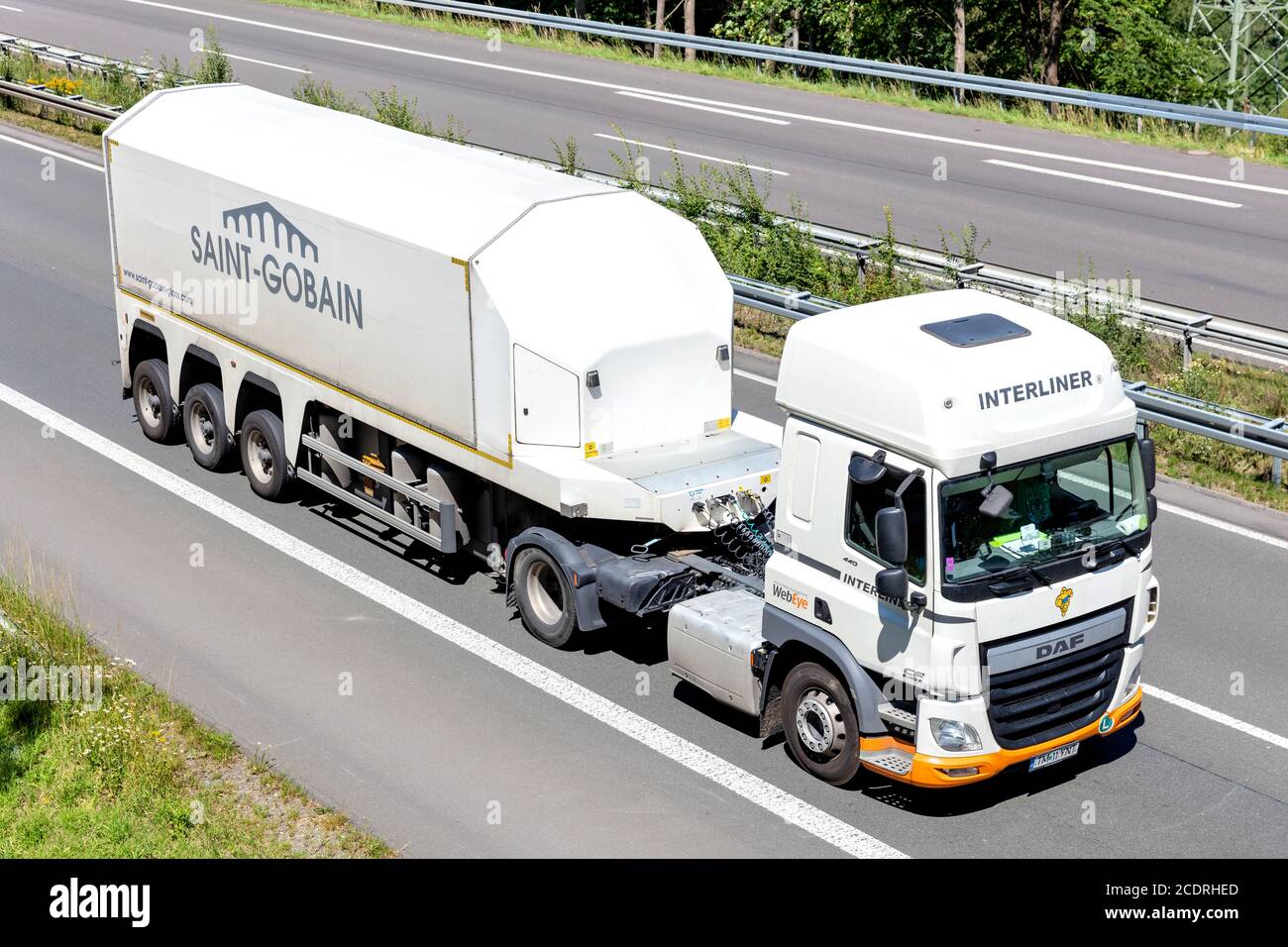 Interliner DAF CF truck with Saint-Gobain glass inloader trailer on motorway. Stock Photo