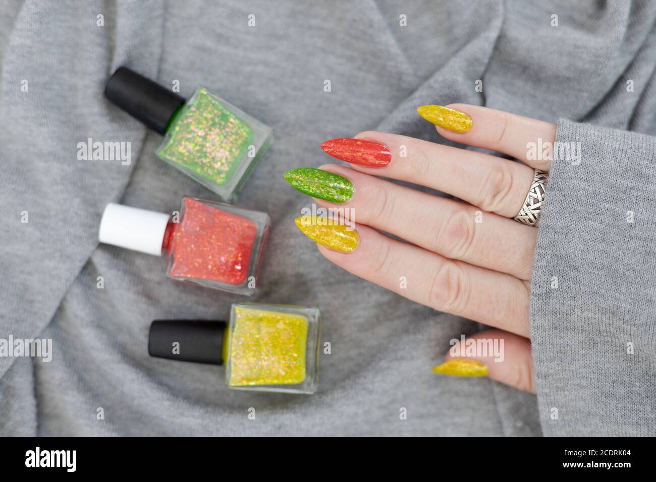 Female hand with long nails and multicolored manicure, bottles of nail