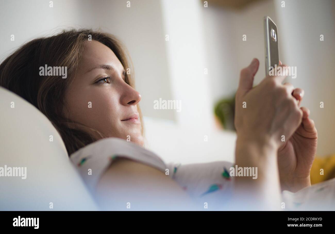Young woman using mobile phone at home smiling Stock Photo