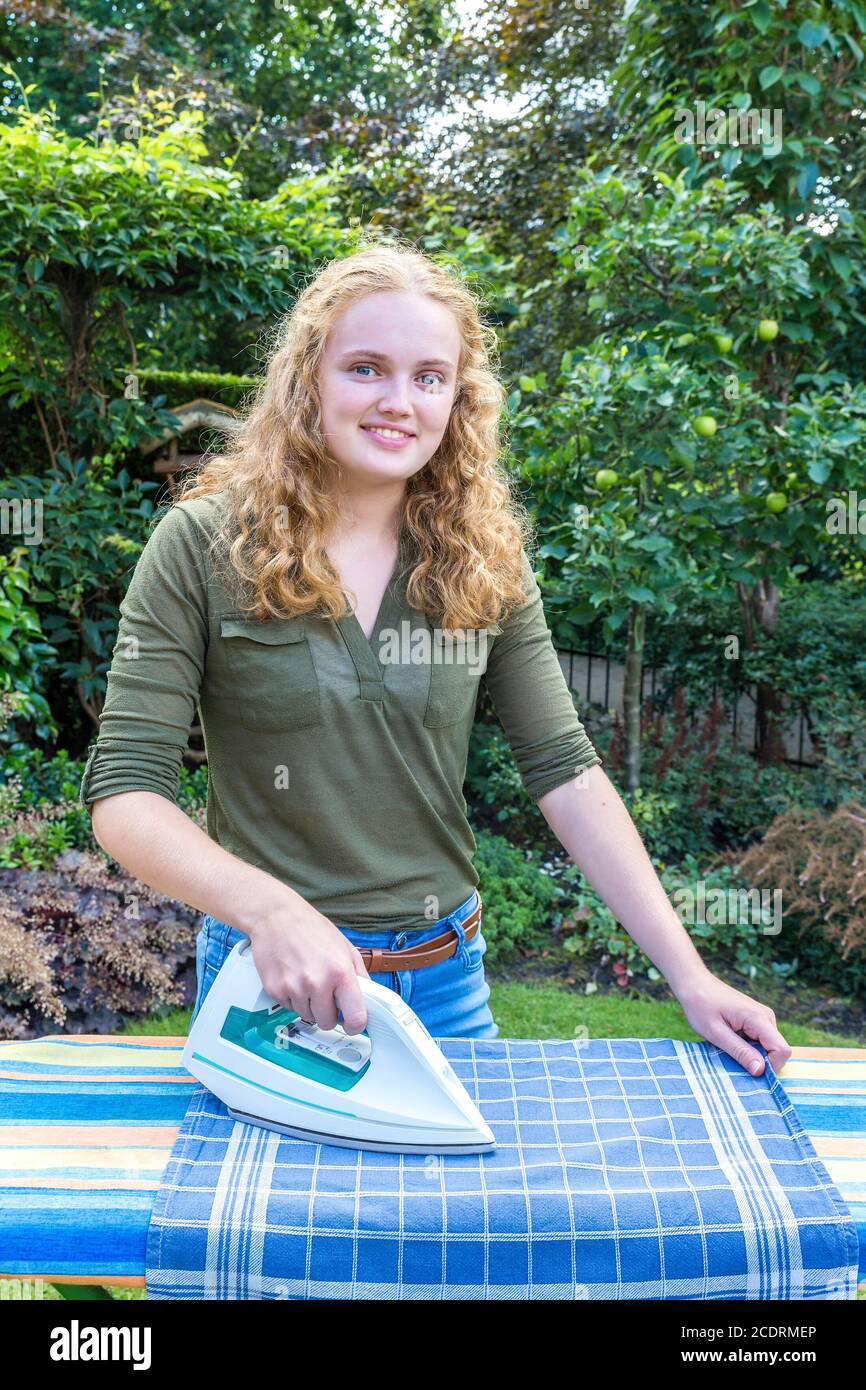 Young caucasian woman ironing tea towel outside Stock Photo