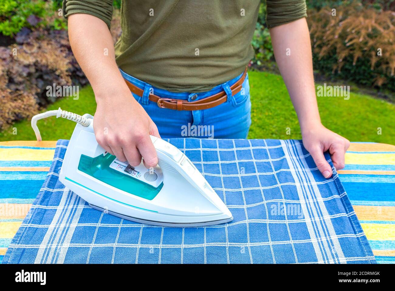 Young woman ironing tea towel outside Stock Photo