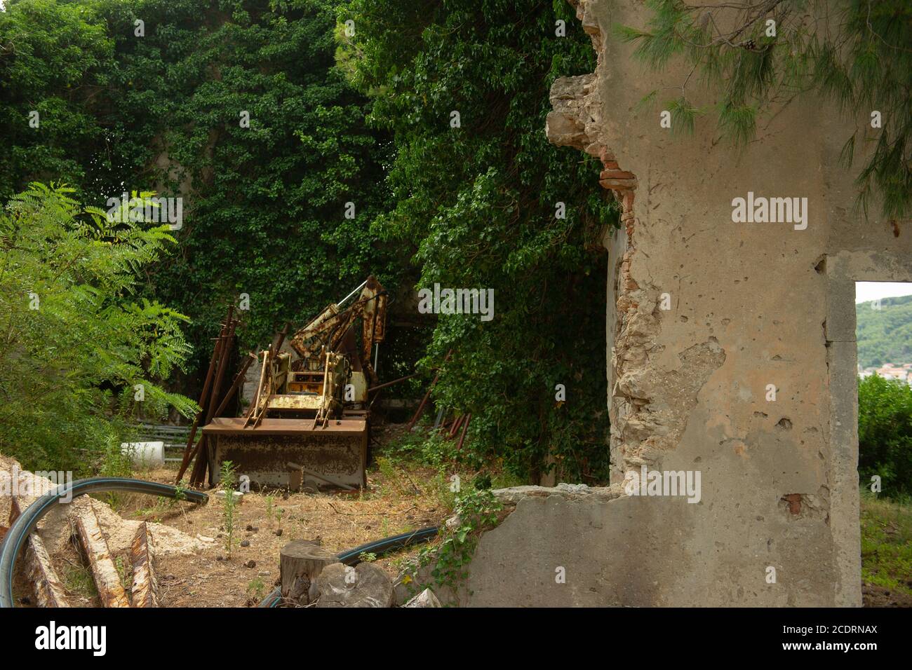 A rusty tractor loader sits abandoned in a collapsed barn. Stock Photo