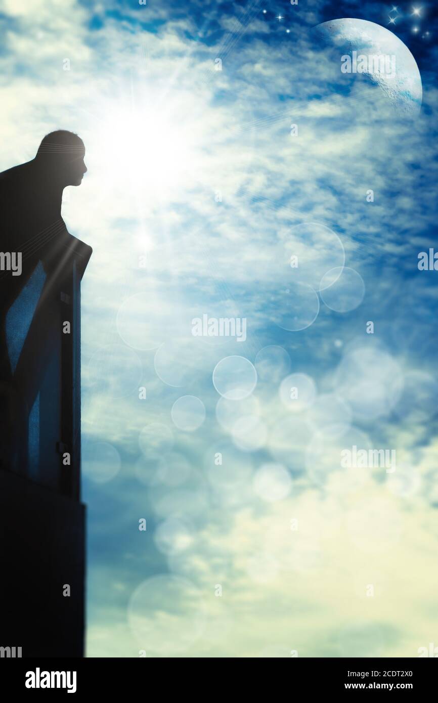 Man on balcony in backlight looking in a blue sky with sun, moon, stars, clouds and bokeh Stock Photo