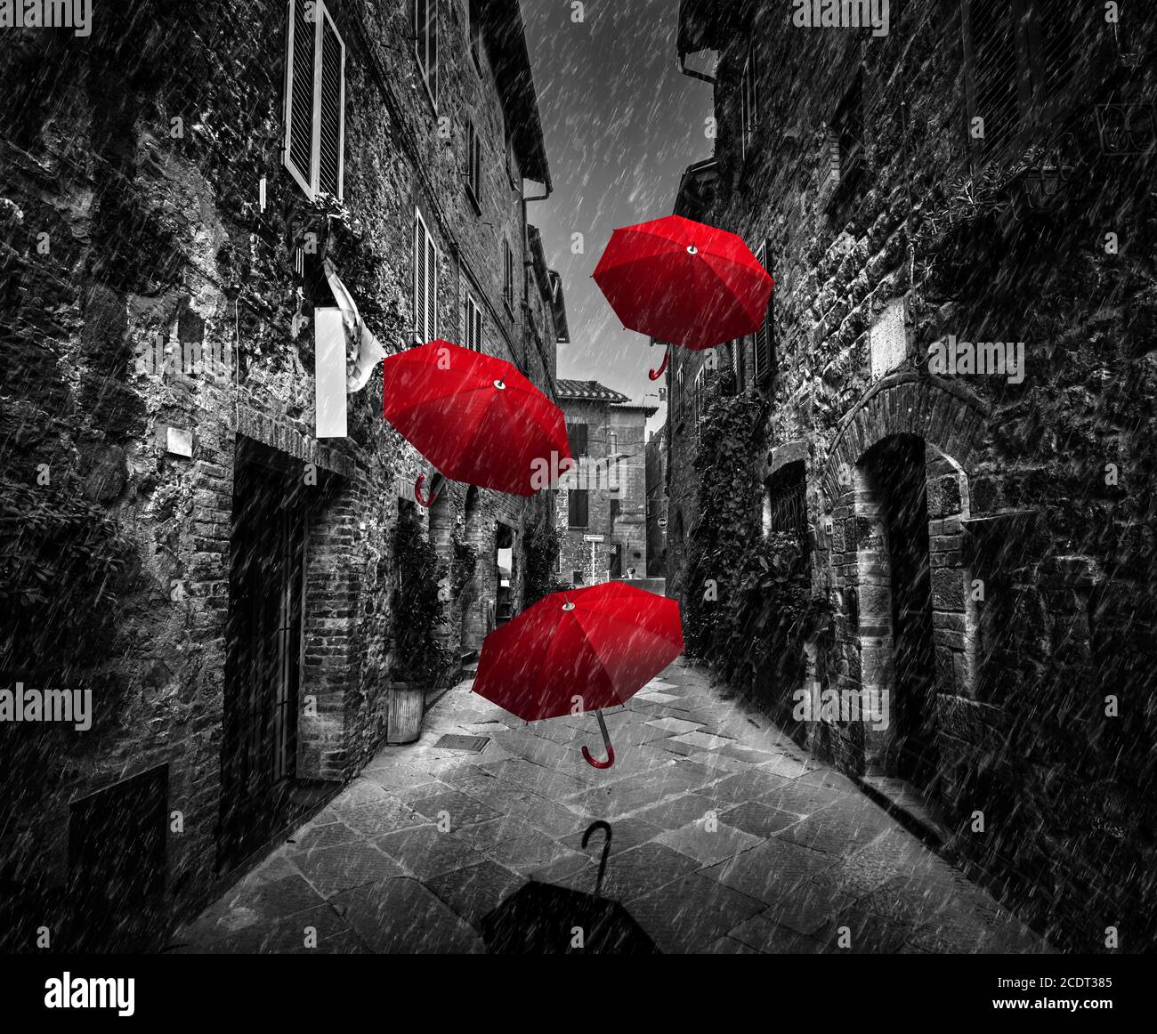 Umrbellas flying with wind and rain on dark street in an old Italian town in Tuscany, Italy Stock Photo
