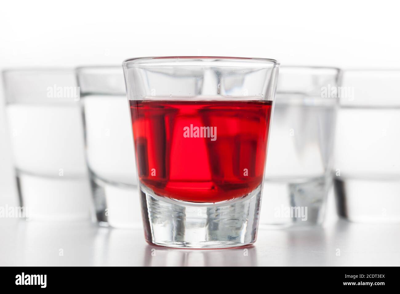 Glasses of alcohol. One red flavoured, the others clean vodka. Stock Photo