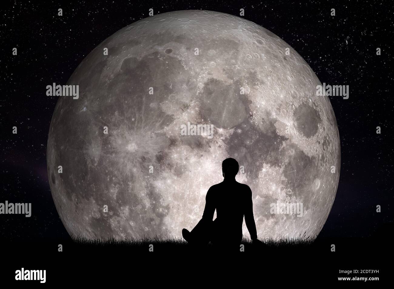 Man sitting alone on grass and looking on moon. Imagine the future concept. Stock Photo