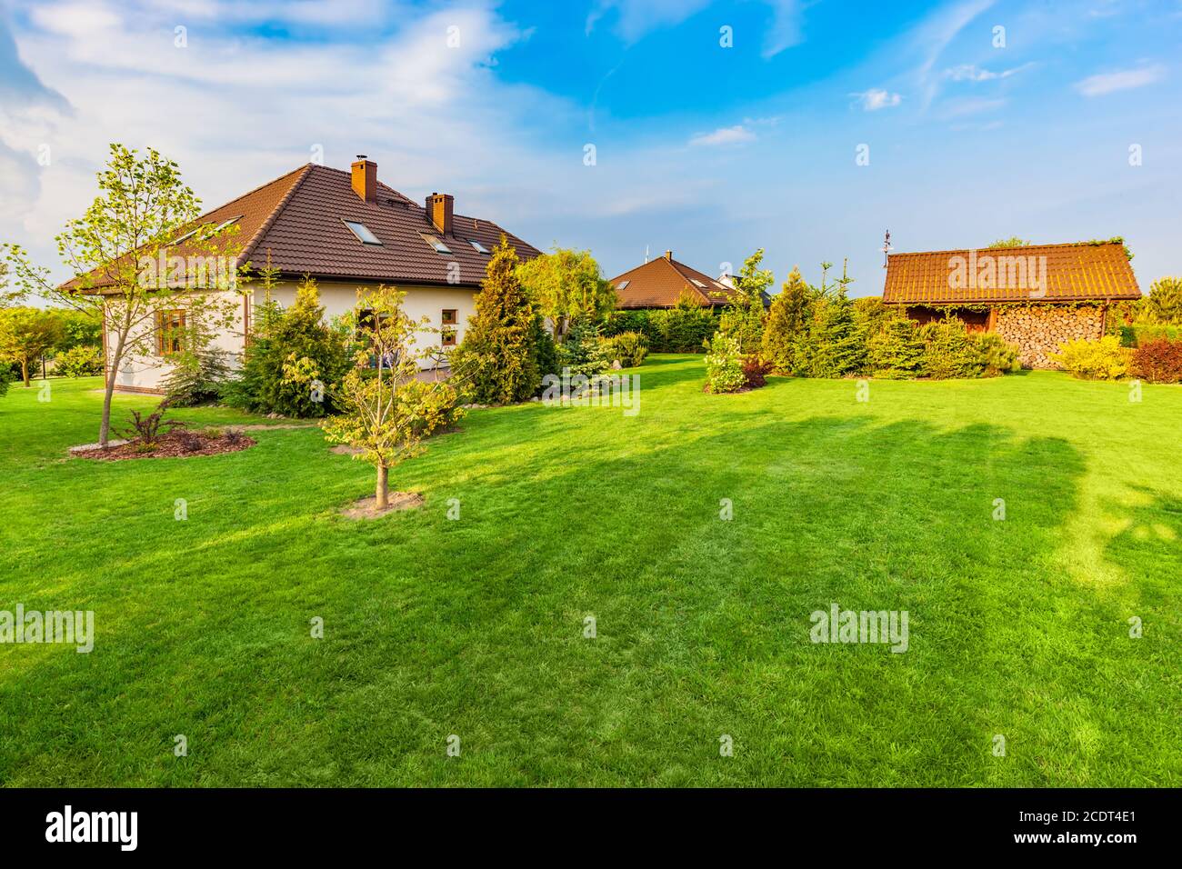 Backyard of a family house. Spacious landscaped garden with green mown grass Stock Photo