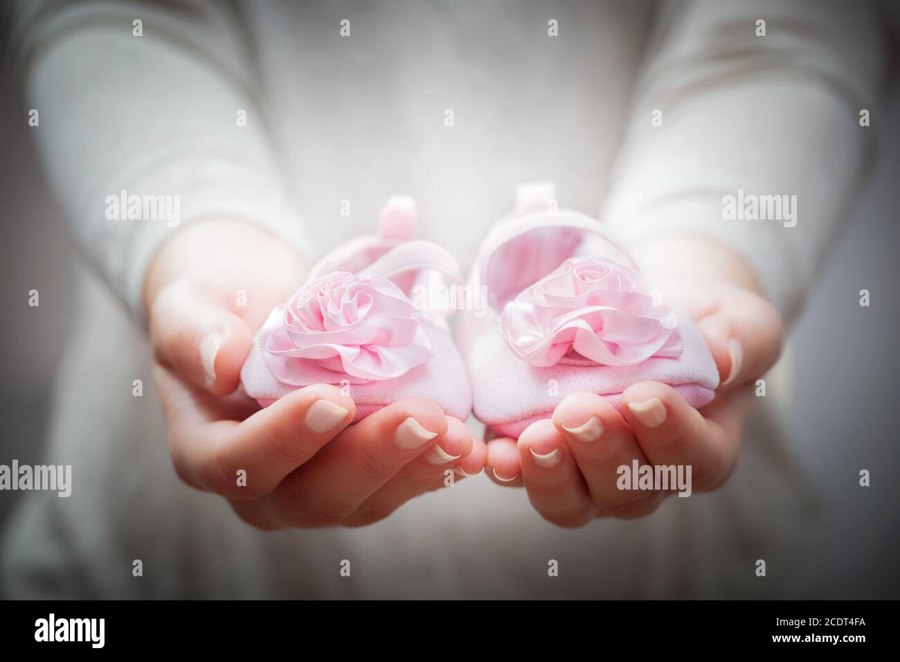 Little baby shoes in woman#39;s hands. Concepts of waiting for a child, charity, mother etc. Stock Photo