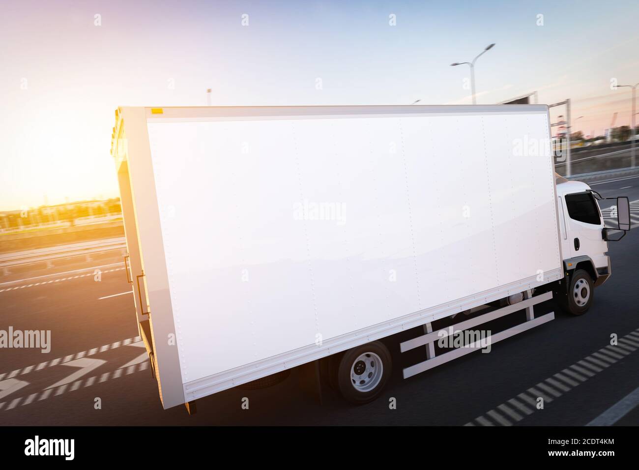 Commercial cargo delivery truck with blank white trailer driving on highway. Stock Photo