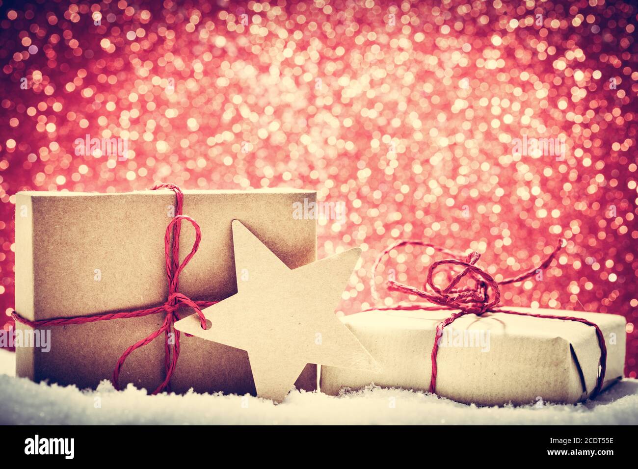 Retro rustic Christmas gifts, presents in snow on glitter background Stock Photo