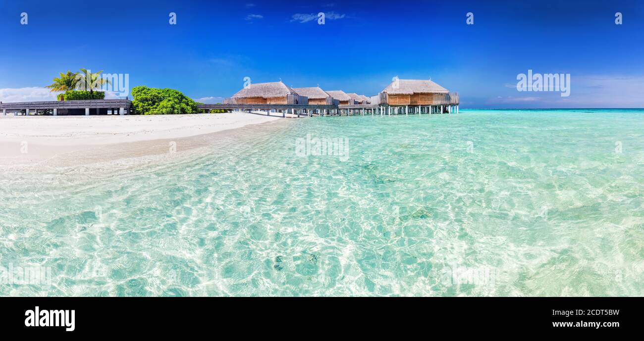 Panorama of wide sandy beach with water villas on a tropical island in Maldives Stock Photo