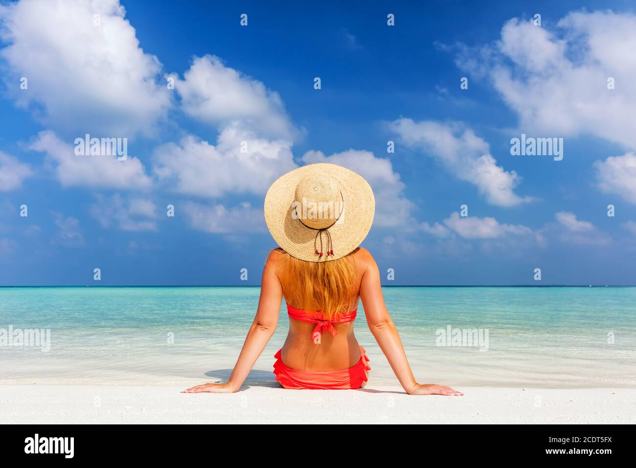 Beautiful young woman in sunhat sitting relaxed on tropical beach in Maldives Stock Photo