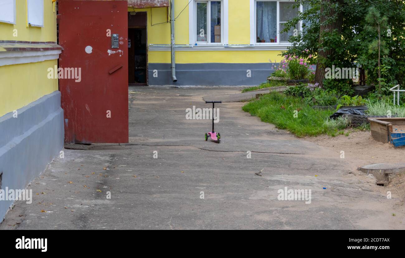 Children's scooter stands in the city yard on the asphalt Stock Photo