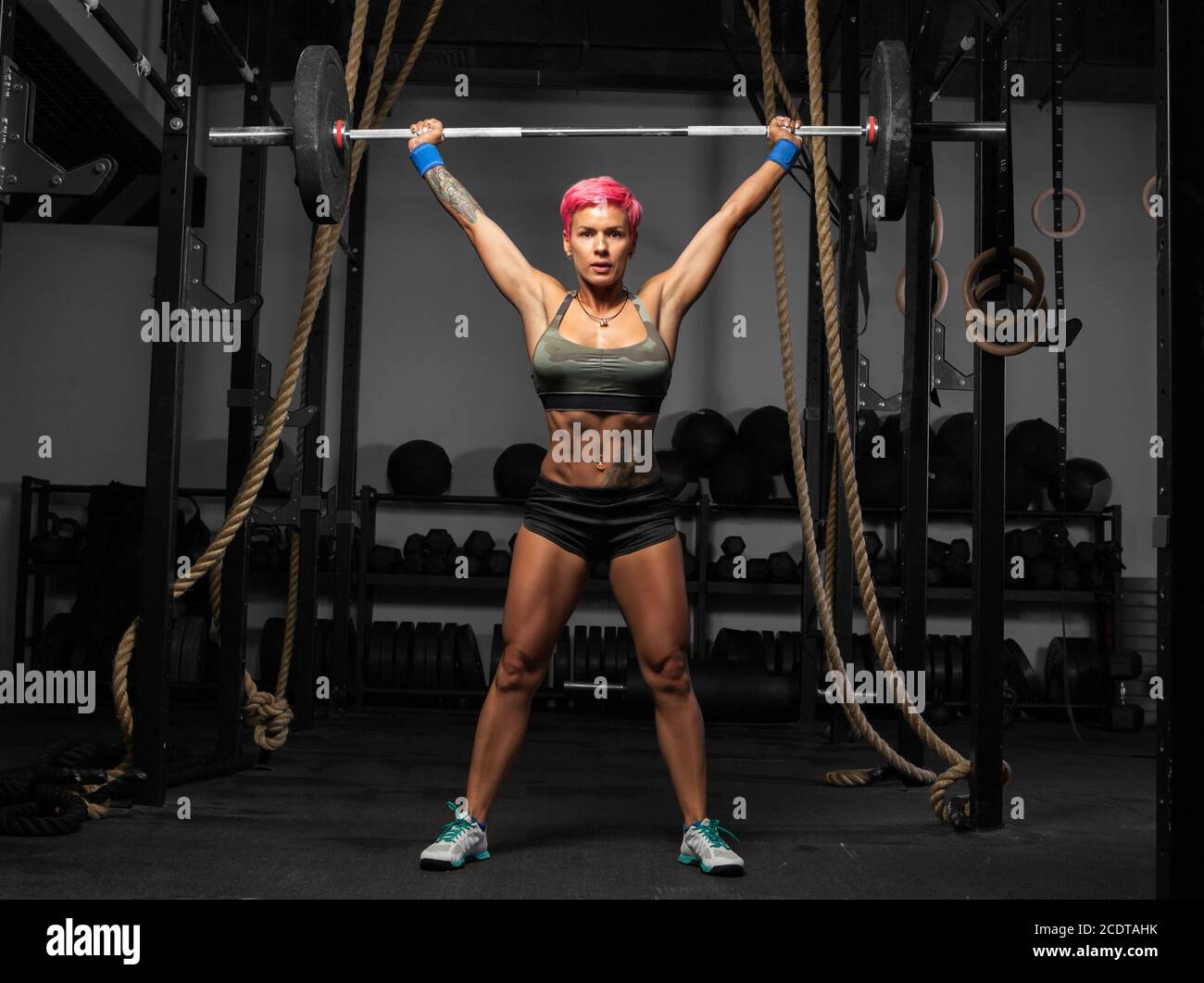 Full length portrait of muscular woman in a gym doing heavy weight