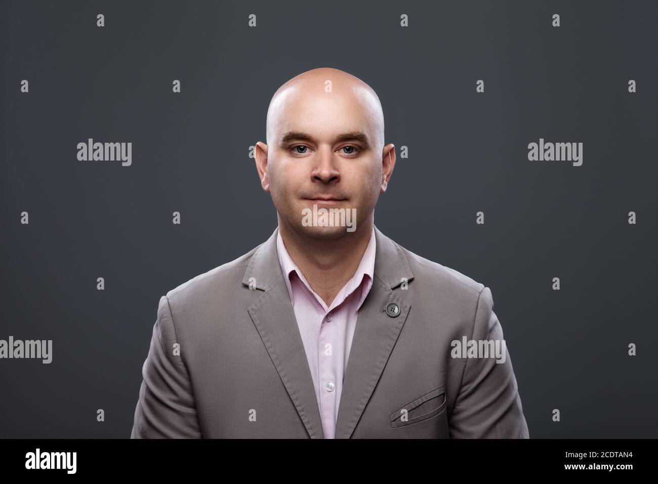 Portrait of a bald affable man in a suit against a dark background Stock Photo