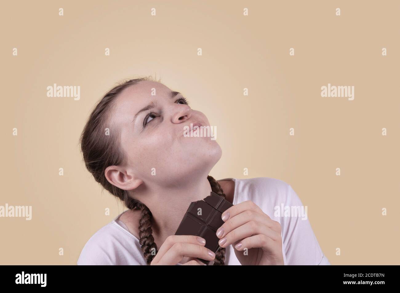 The girl tastes chocolate. The girl is enjoying the taste of chocolate. Delight in the taste of chocolate. Chocolate Day. Sweets day. The girl is shot Stock Photo