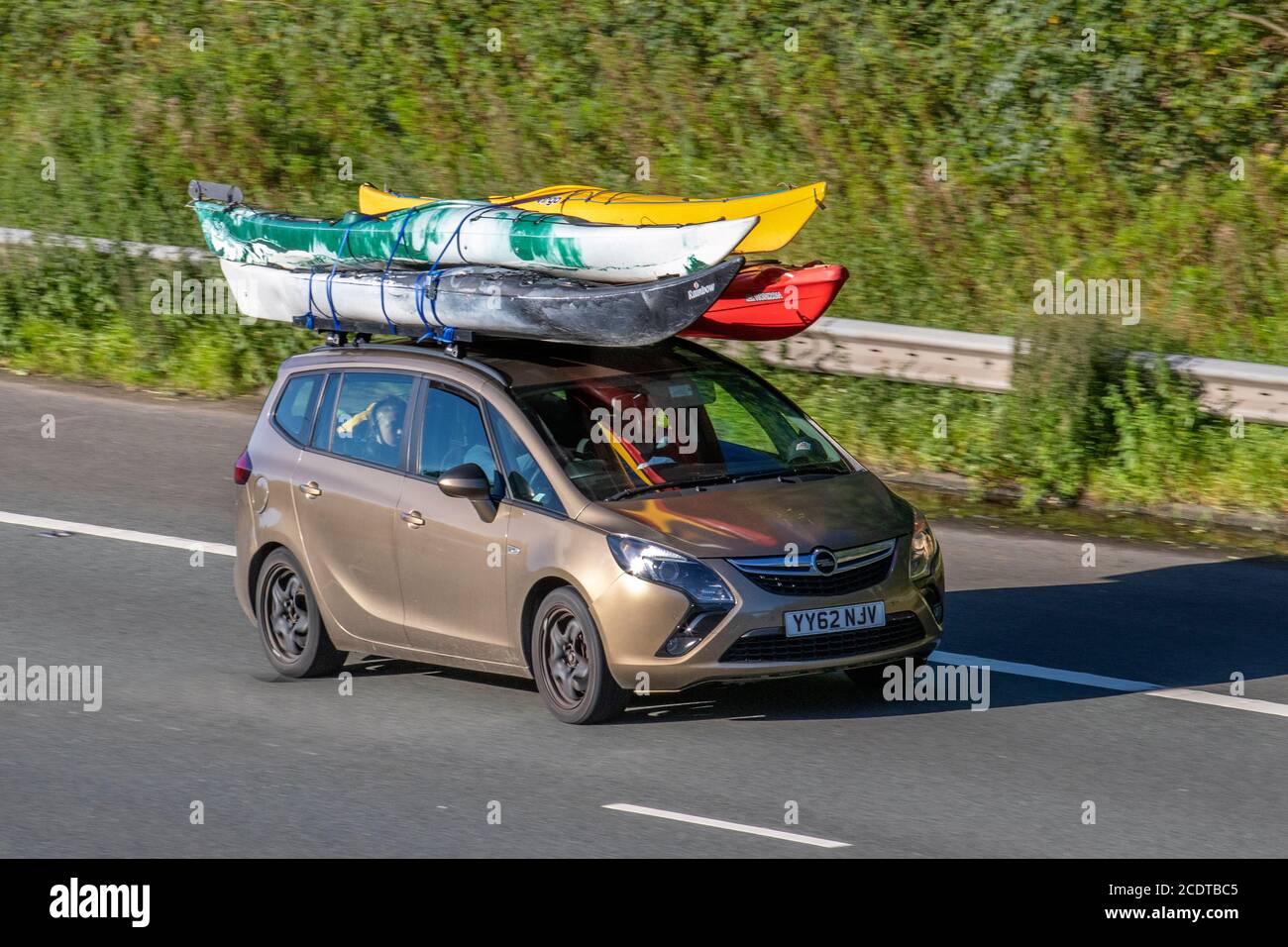 2012 bronze Vauxhall Zafira Tourer Exclusiv CD carrying canoes on roof rack;Vehicular traffic moving vehicles, cars driving vehicle on UK roads, motors, motoring on the M6 motorway highway network. Stock Photo
