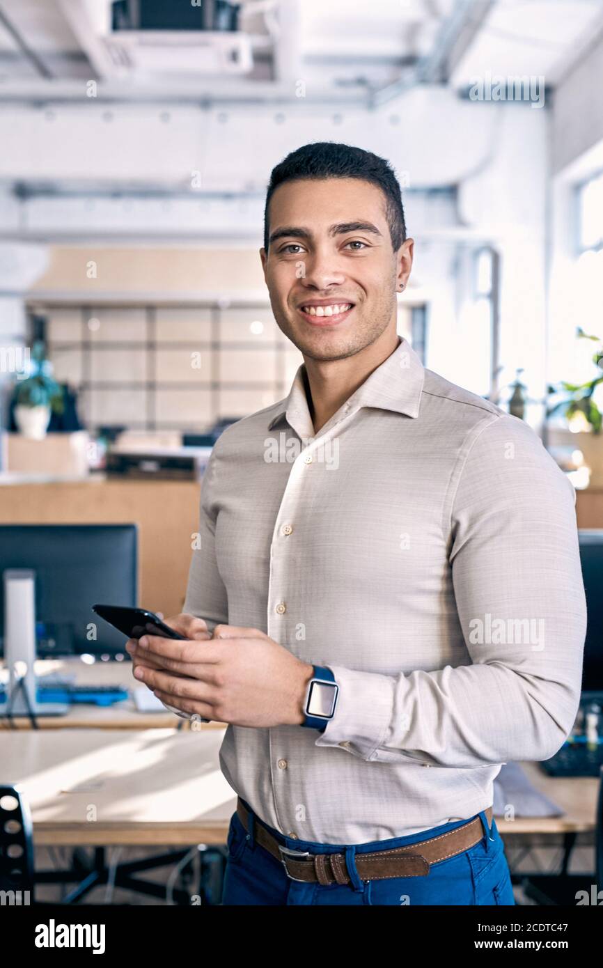 Confident man using smartphone and standing in office Stock Photo