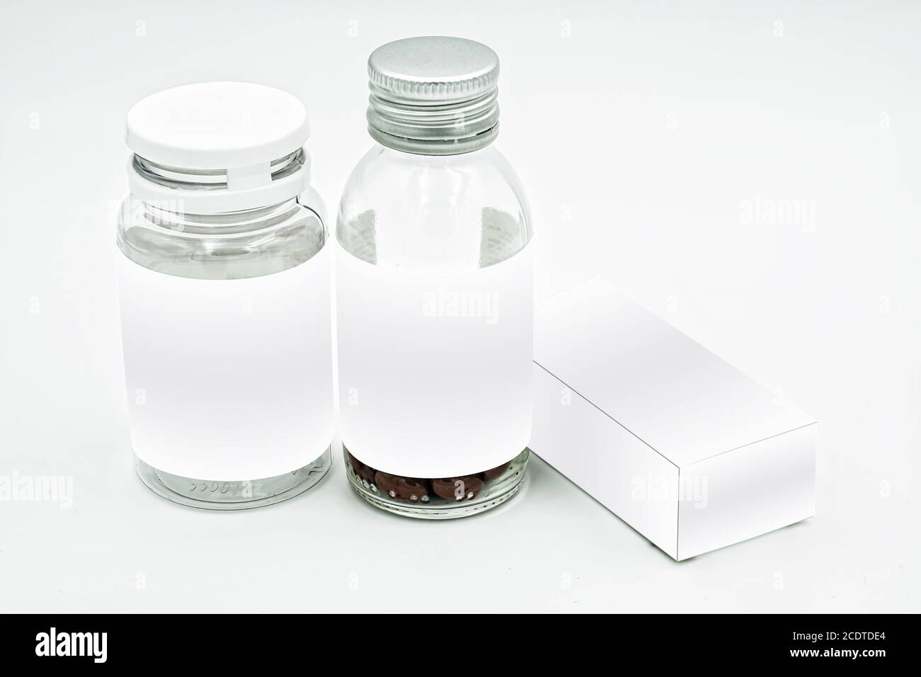 Two pill bottles, one medicine box, with white label mockup, on a white background, ideal for pharmaceutical and research use Stock Photo
