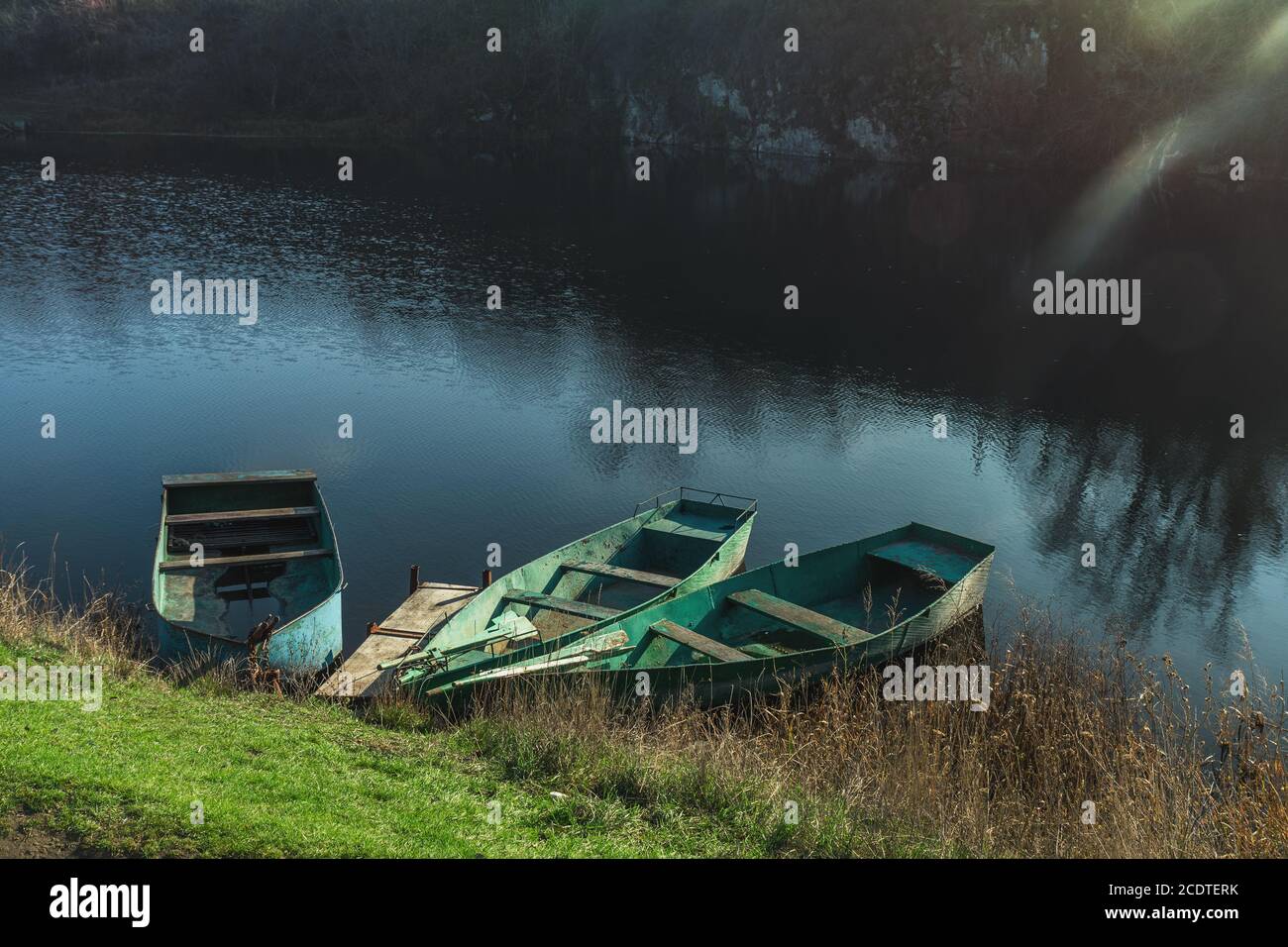 Three wooden boats peacefully resting on an autumn river at the sunset Stock Photo