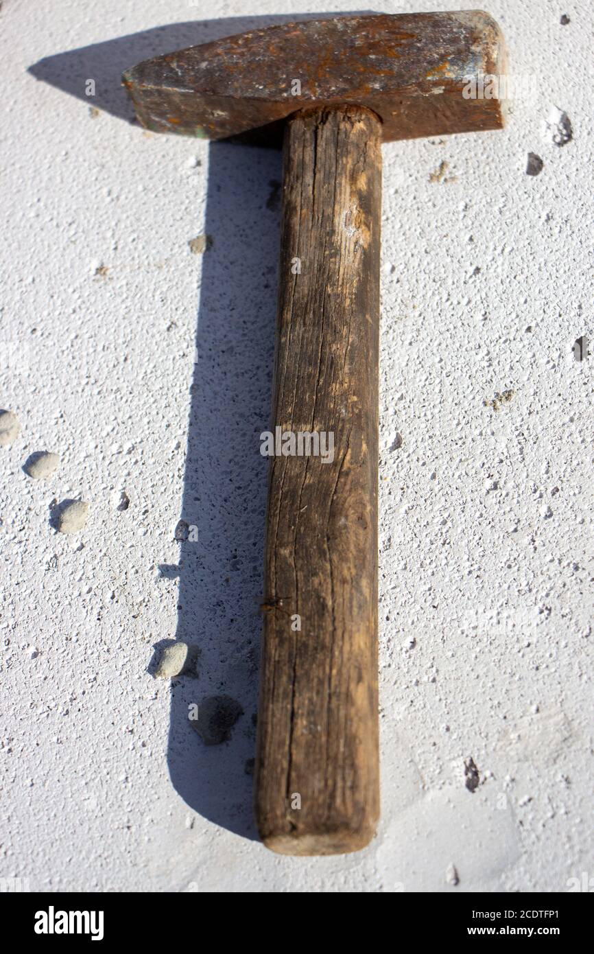 An old hammer on a white foam concrete block from which the shadow falls Stock Photo