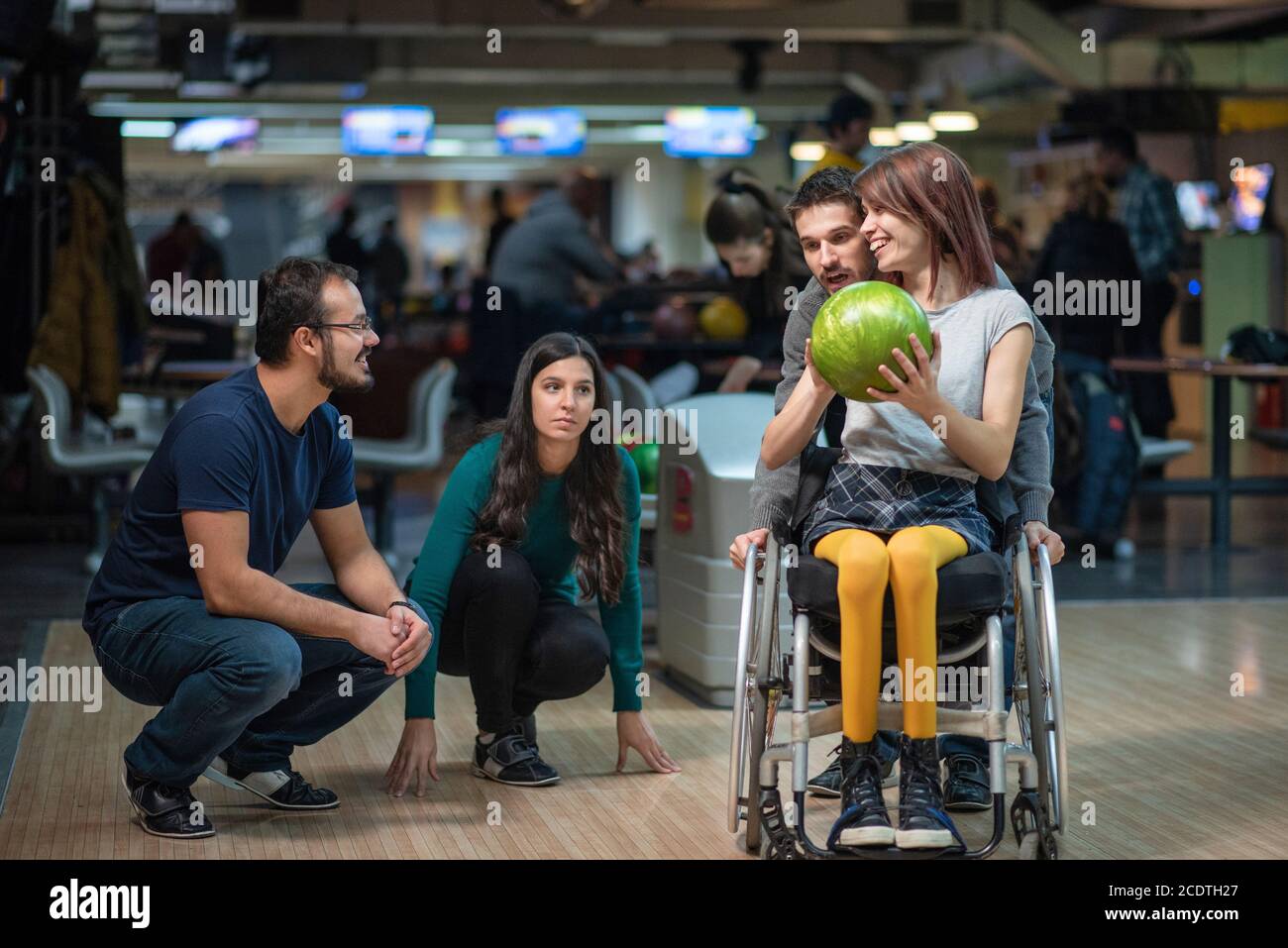 Disabled woman in a wheelchair bowling with friends Stock Photo