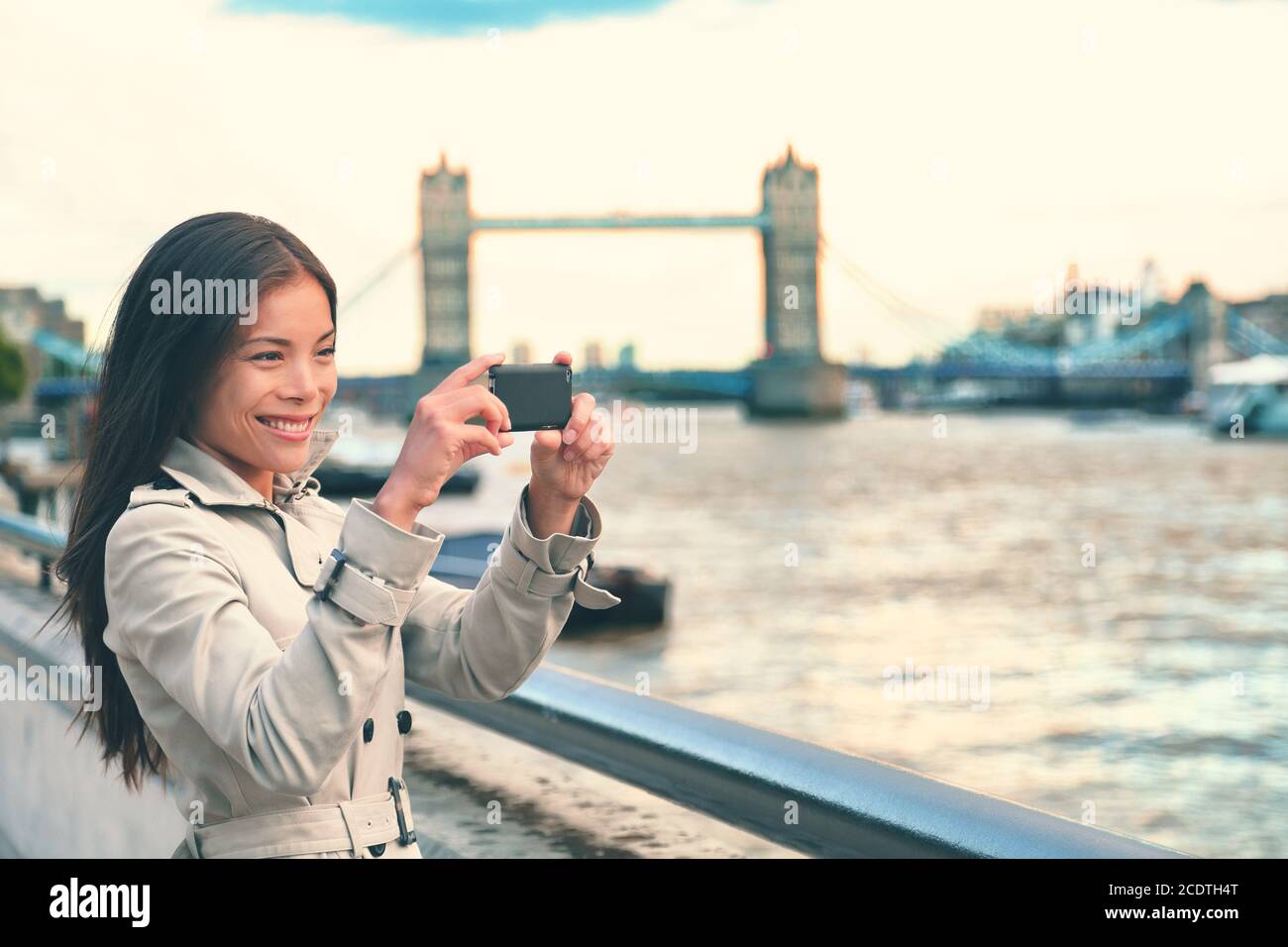 London woman tourist taking photo of Tower Bridge with mobile smart phone camera. Girl enjoying view over the River Thames, London, England, Great Stock Photo