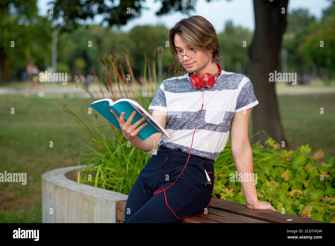 Young gay man reading a book in a park Stock Photo