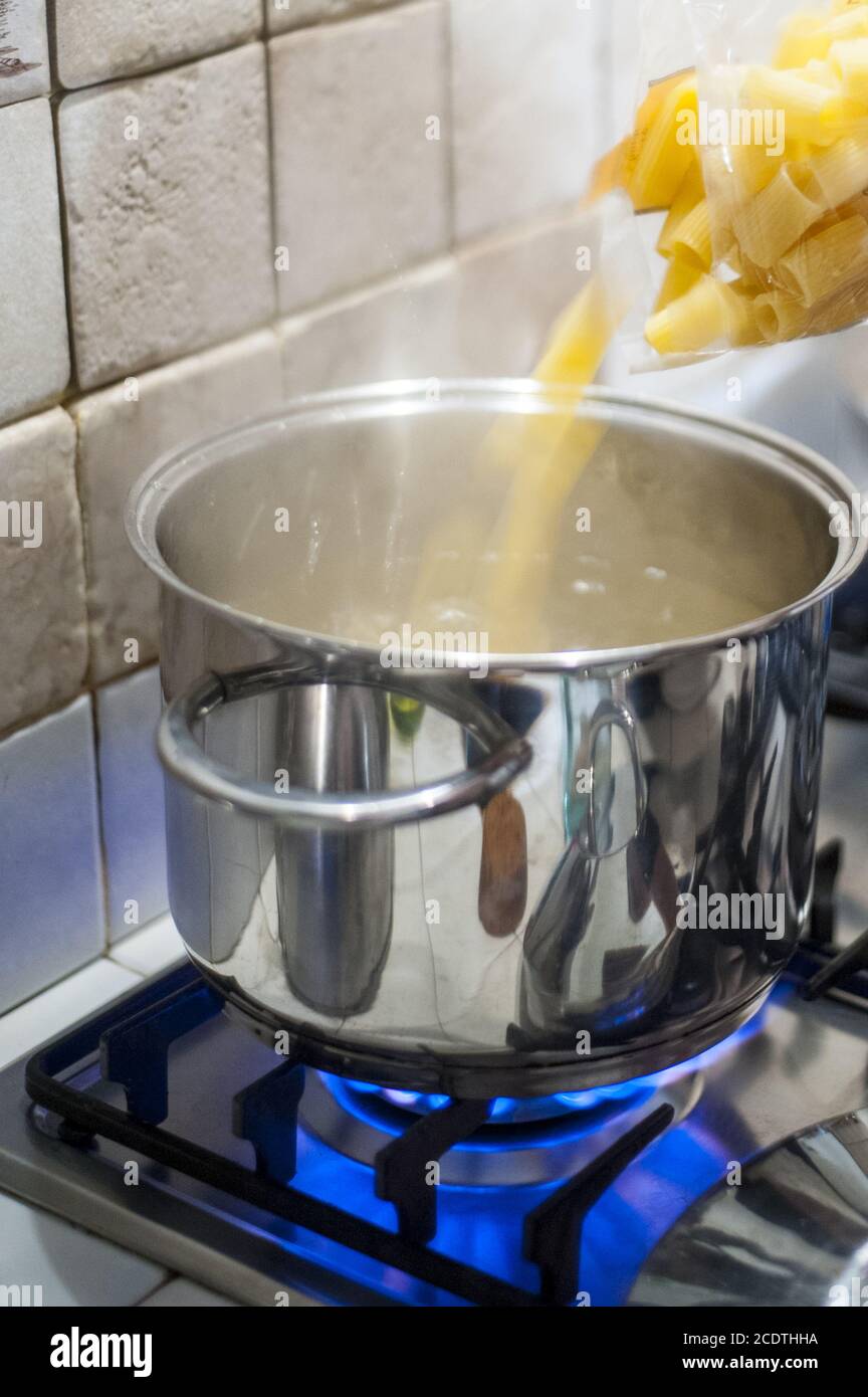 throw pasta into the pot of water on the stove fire Stock Photo Alamy