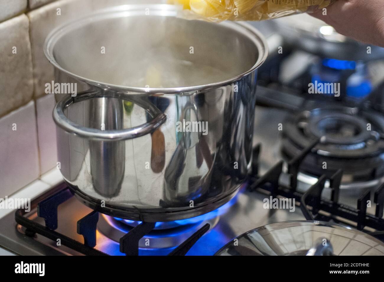 throw pasta into the pot of water on the stove fire Stock Photo Alamy