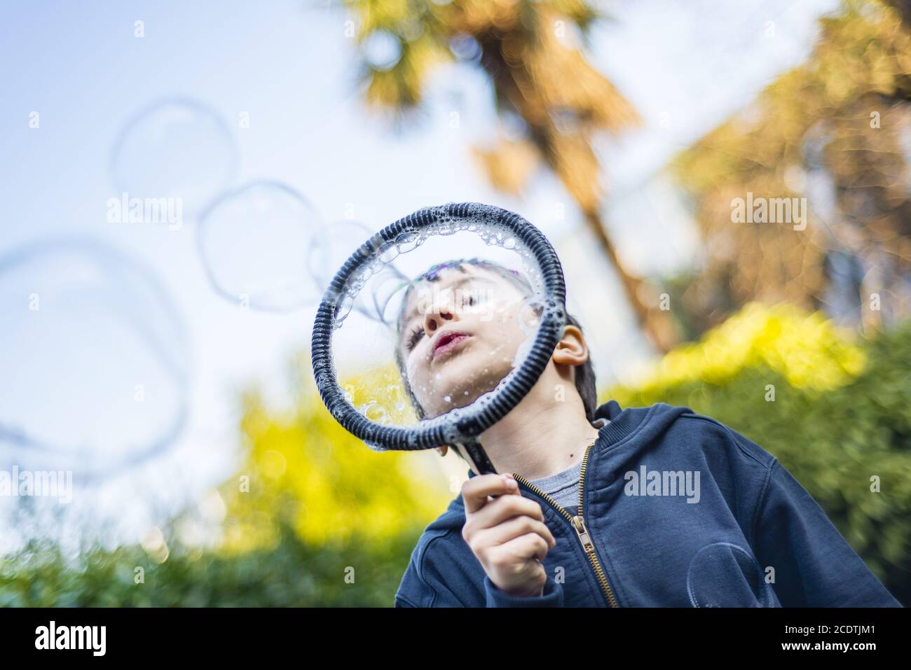 7-year-old child outdoors in the garden in winter makes big soap bubbles Stock Photo