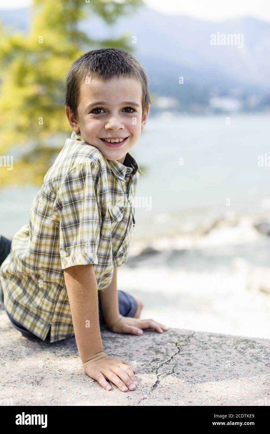 portrait of 9 year old boy smiling with colorful shirt sitting on a
