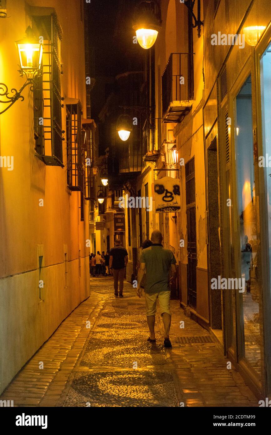 Malaga, Spain - June 24: Tourists walk past the dimly lit street of Malaga, Spain, Europe at night Stock Photo
