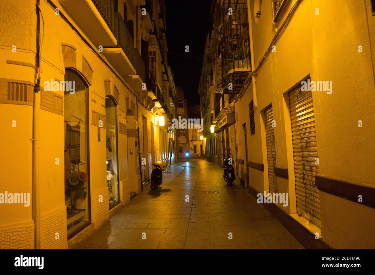 Cobblestone street lit with street lamps at night in Malaga, Spain ...